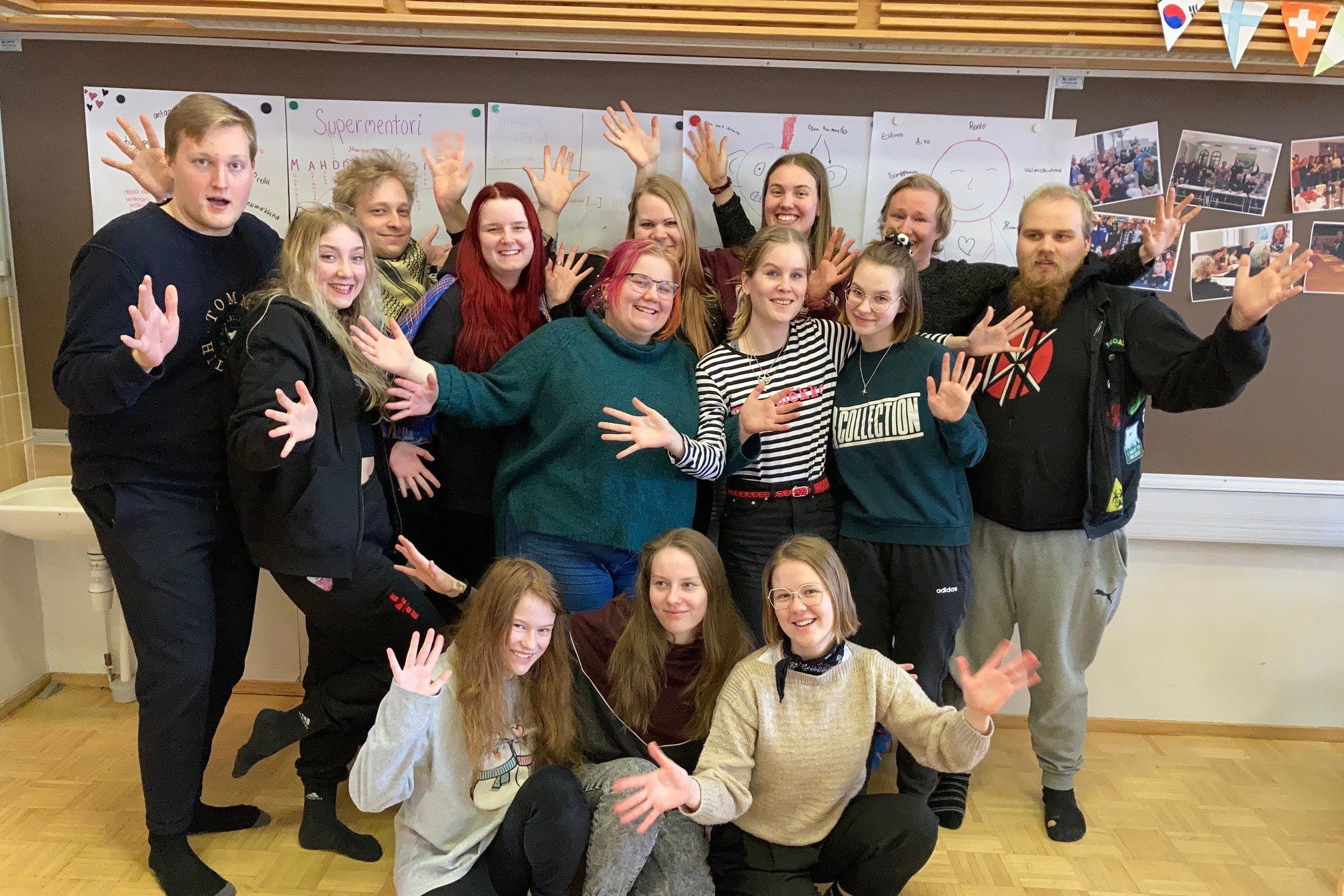 Ryhmäkuva1 Joukko nuoria seisoo yhdessä kädet levitettynä.